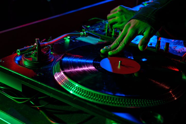 cropped view of DJ hands with sound mixer and vinyl in nightclub
