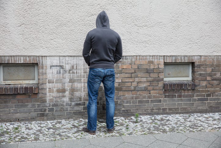 Man urinating on wall