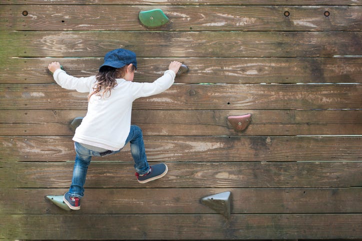 young girl climbs rock wall