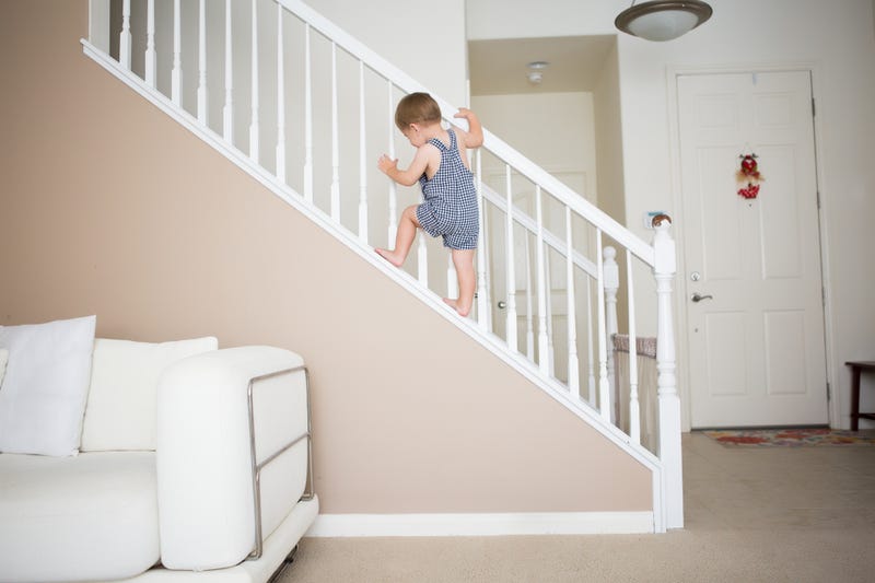 Cute toddler boy is climbing the stairways at home