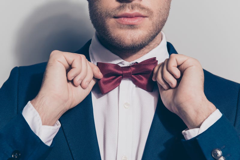 bearded man ties a bowtie at the collar