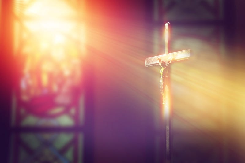 Crucifix in church with ray of light from stained glass