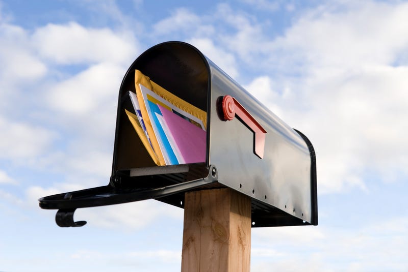 Mail box against a blue sky with clouds.