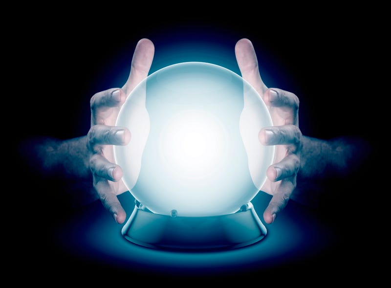  pair of male hands surrounding a crystal ball conjuring up a hologram on an isolated dark studio background