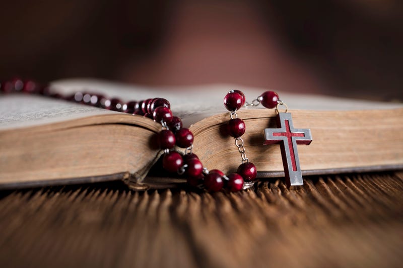 Rosary beads and a cross sit atop a Bible.