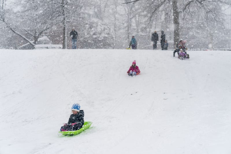 People going sledding in heavy snowfall.