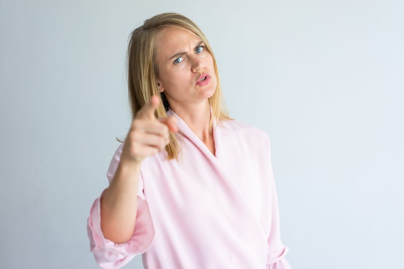 Portrait of irritated young Caucasian woman wearing pink blouse swearing at camera