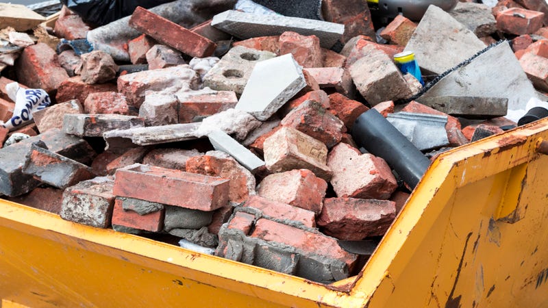 Yellow metal skip full of old bricks - stock photo