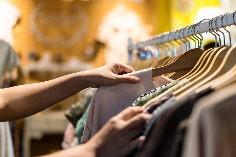 woman selecting shirt from rack of clothes