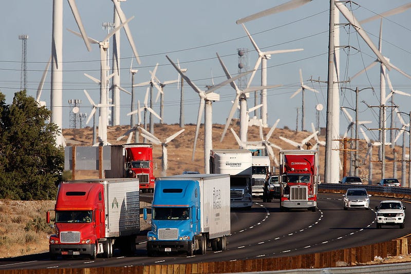 FILE - Emissions-producing diesel trucks and cars pass non-polluting windmills along the 10 freeway on December 8, 2009 near Banning, Calif.