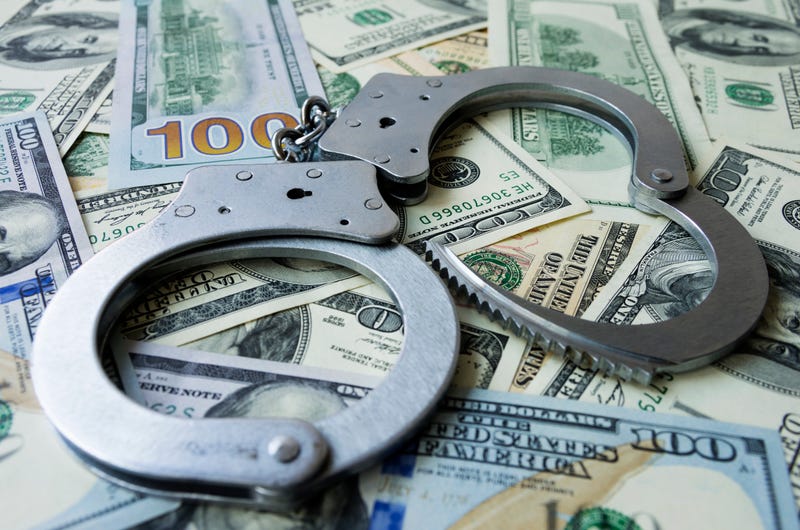 handcuffs on a pile of hundred dollar bills