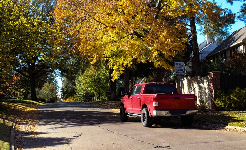 Red pickup truck parked on leafy neighborhood street