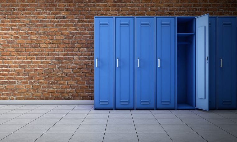 A line of lockers against a brick wall in a school hallway