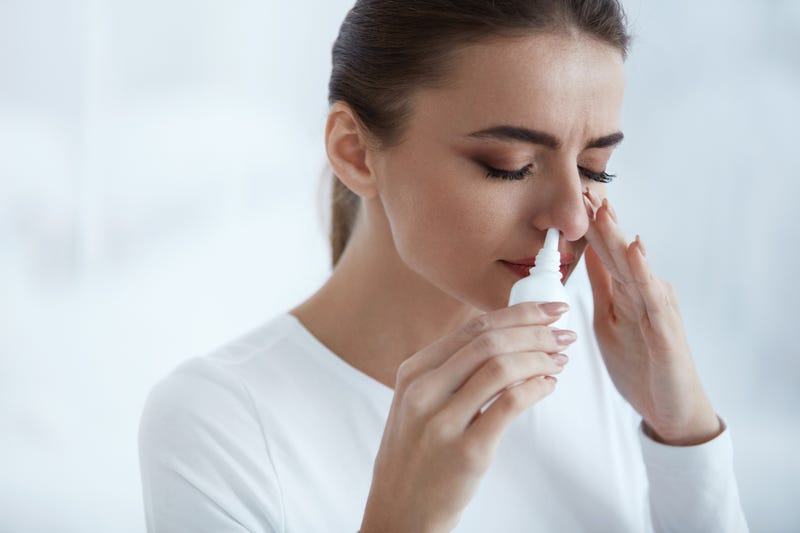 Young woman uses nasal spray while stressed.