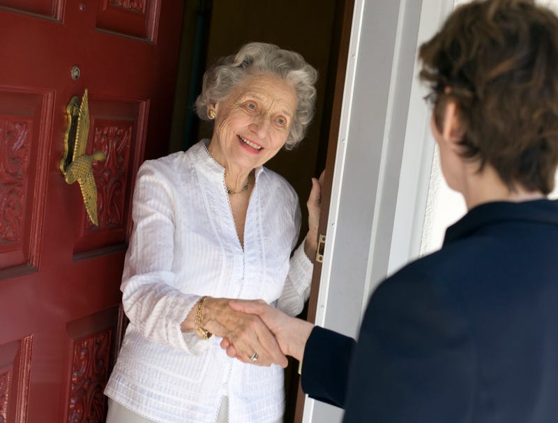 Senior citizen woman answers door stock photo. 