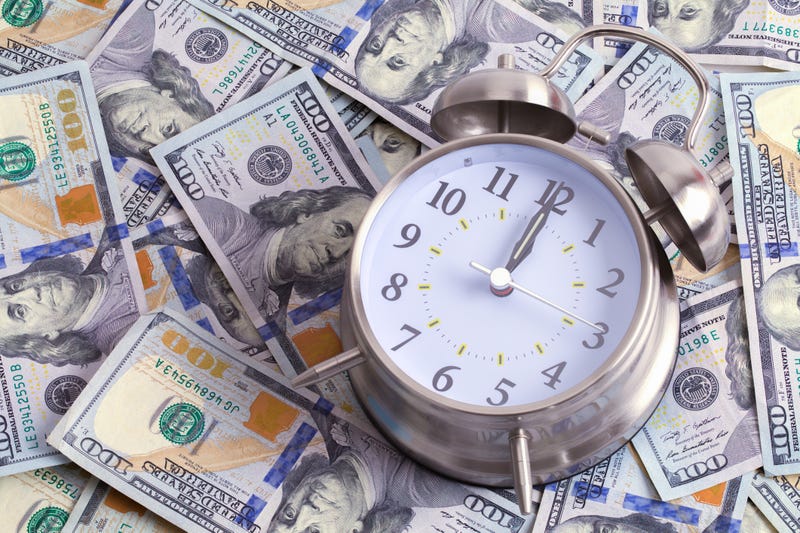 Clock on Top a Large Pile of Hundred Dollar Bills.