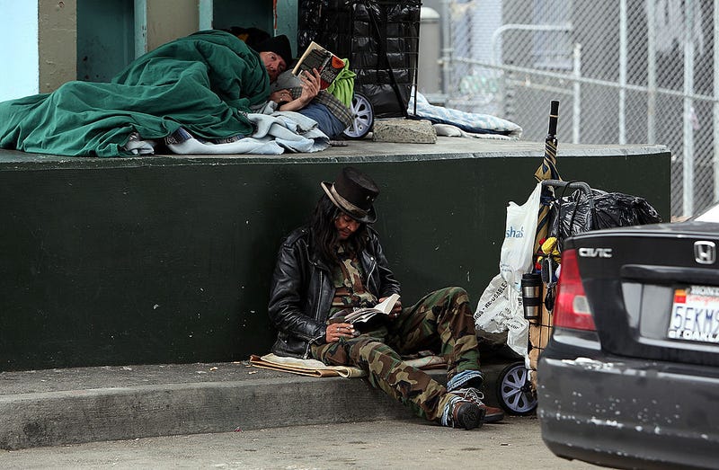 A homeless man named Joe (R) reads a book under an overpass where he sleeps with a friend January 25, 2010 in San Francisco, California.