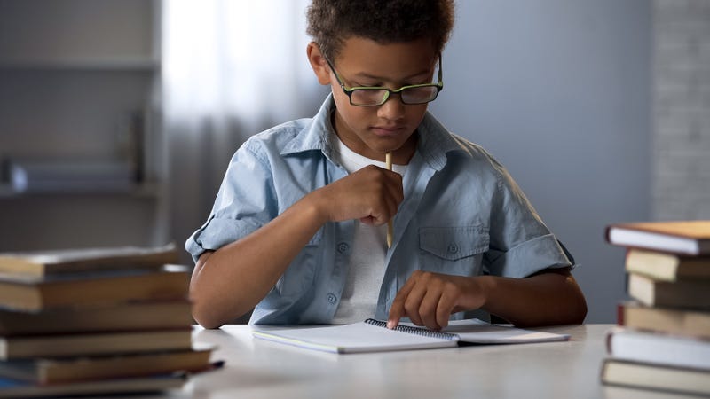 Thinking boy sitting with blank notebook table, writing homework essay, school