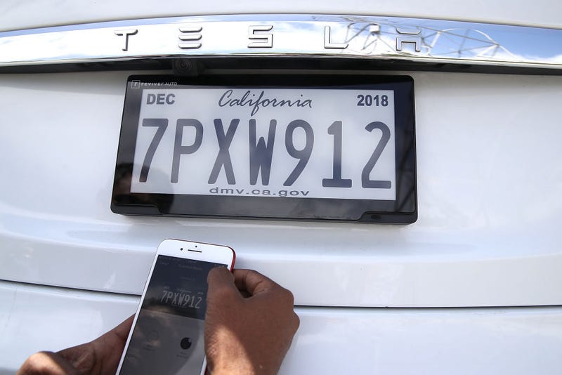 Alok Damireddy uses a smart phone app to make adjustments to a digital license plate made by Bay Area company Reviver Auto, part of a pilot project with the state Department of Motor Vehicles, at Reviver Auto headquarters on May 30, 2018 in Foster City, California.