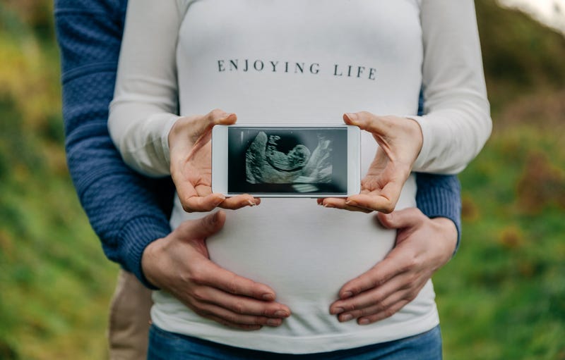 Pregnant showing ultrasound on the mobile with her partner