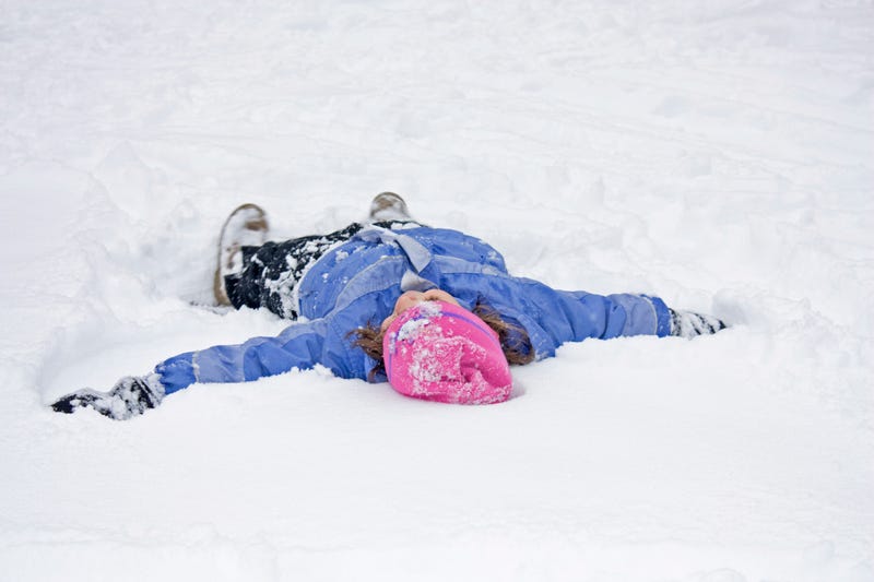 Little Girl having fun making a Snow Angel in the First Snowfall of the Year