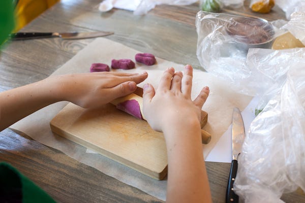 Young girl rolling dough on cutting board