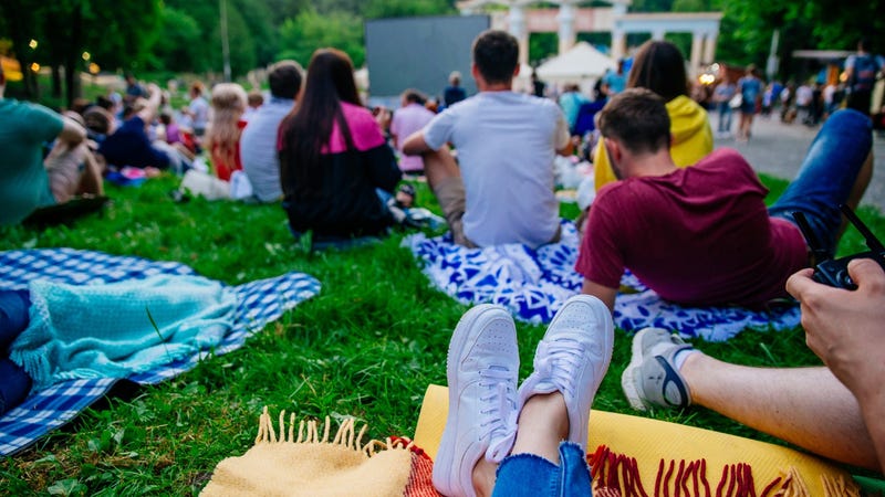 People sitting on blankets watching an outdoor movie in a city park