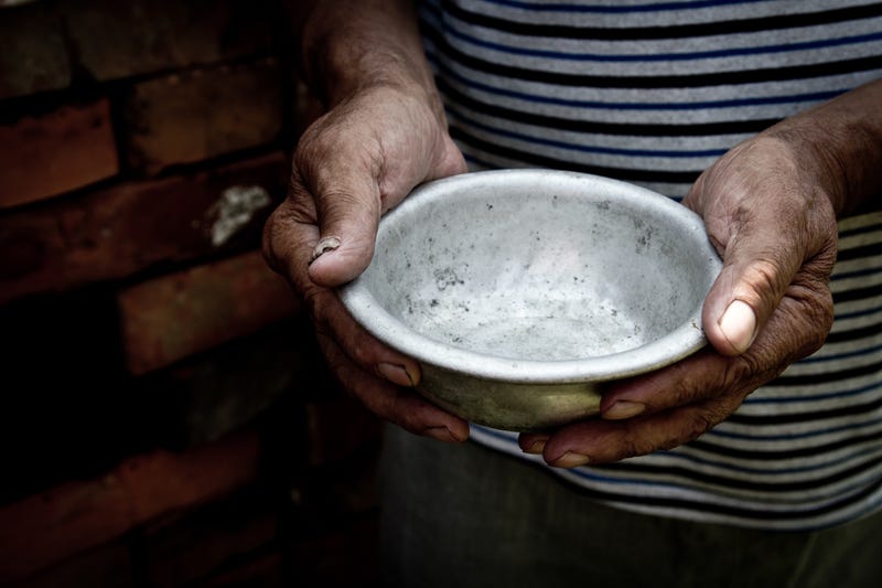 Man holding empty weathered metal bowl, representing food insecurity