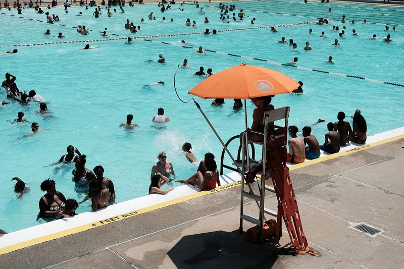 People enjoy a hot afternoon as a lifeguard watches at the Astoria Pool in Queens