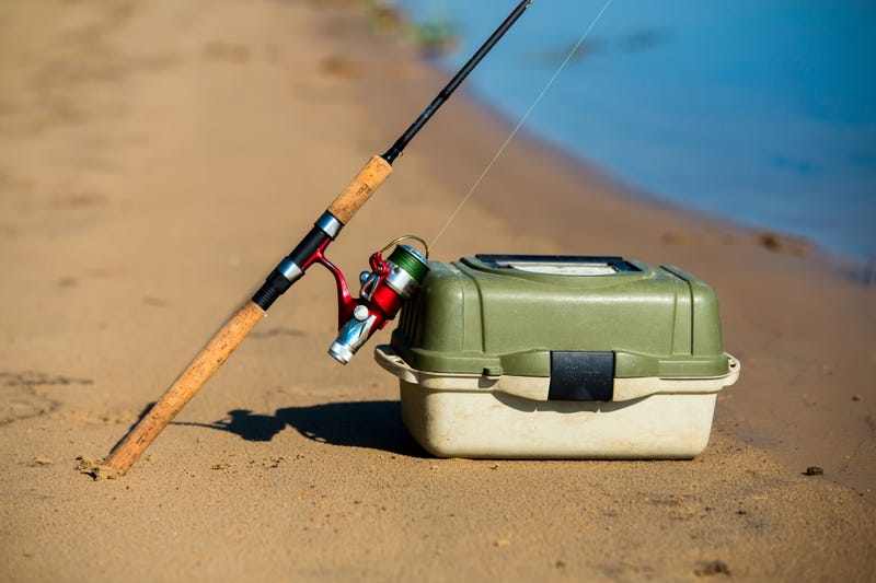 Fishing pole and tackle box on a river shore.