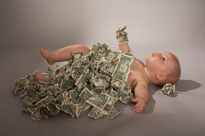 Adorable newborn fast asleep in a basket wearing a hat, glasses, and bow-tie and holding a one hundred dollar bill in US currency. Room for your text.