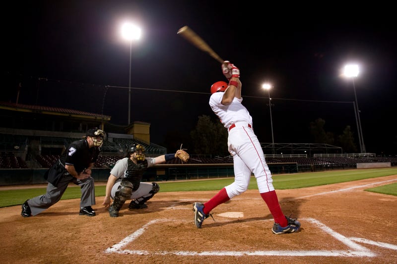 USA, California, San Bernardino, baseball players with batter swinging 