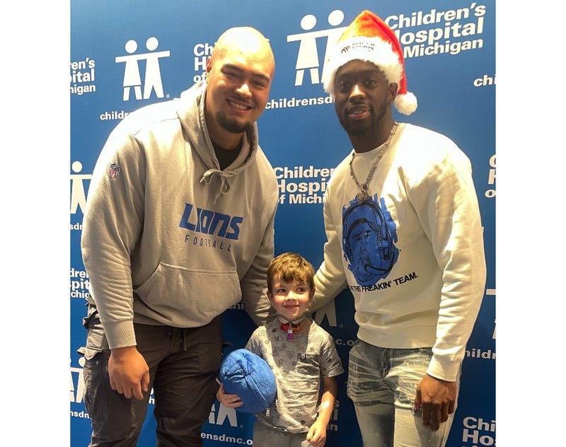 Detroit Lions players Giovanni Manu, left, and Terrion Arnold, right, with patient