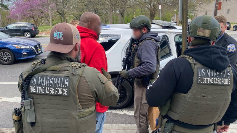 U.S. Marshals capture Keith Holmes and escort him into their vehicle.