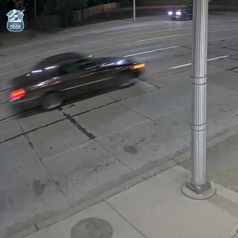 A dark colored older model sedan caught on surveillance driving on road 