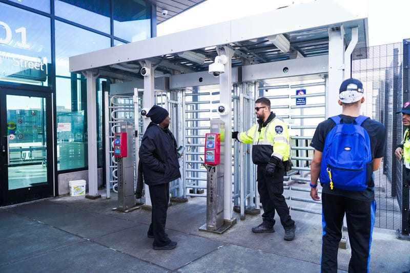 A passenger speaks with a guard at a MetroLink station which has received updated security turnstiles.