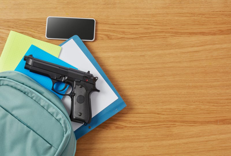 A gun sits atop a student's school supplies