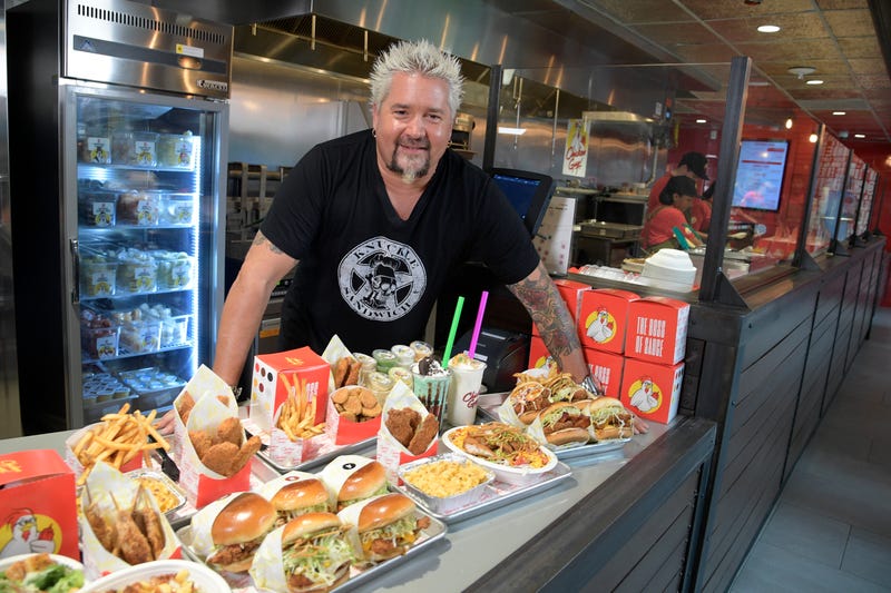 Celebrity chef Guy Fieri posing with array of food from Chicken Guy!