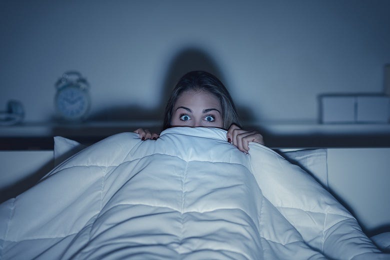 woman in bed watching horror movie