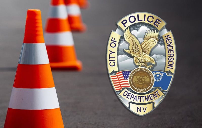 A Henderson Police Department badge, alongside cones marking a traffic accident