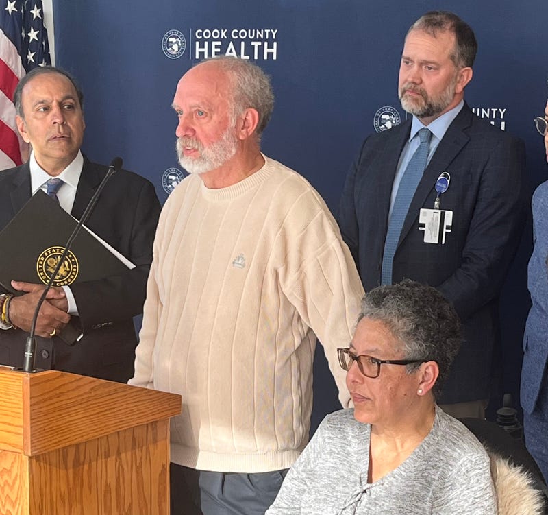 Doug Butchart (center) discusses his family's experience with the ACA marketplaces during an appearance in Bronzeville. His wife Shadene, who is being treated for ALS, is seated in a wheelchair to his left.
