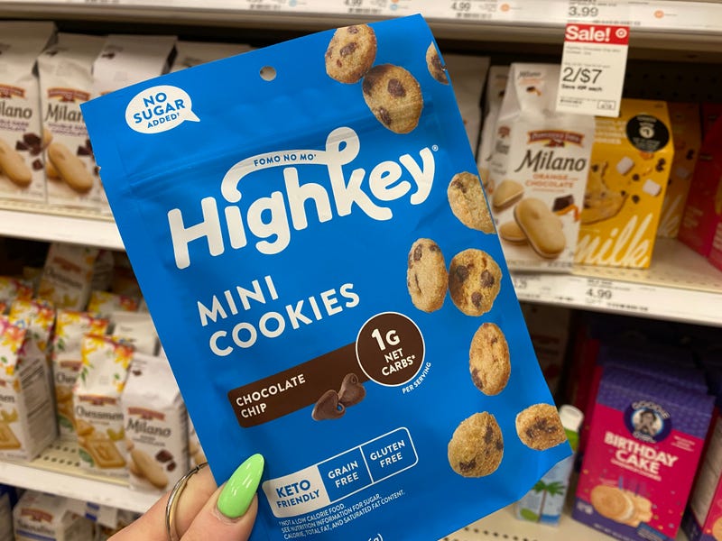 holding package of Highkey mini cookies in front of store shelves