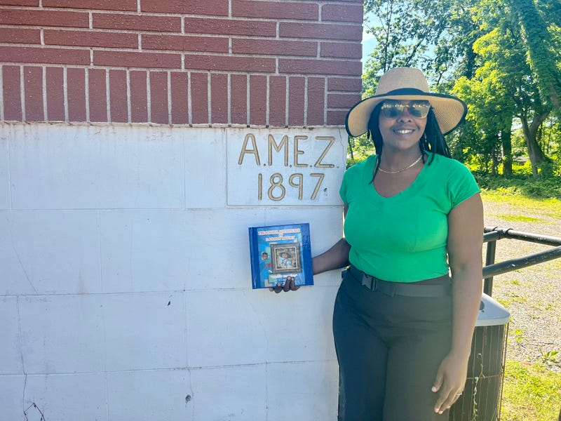Janise LaBoard holding her children's book in front of Rossville A.M.E. Zion church