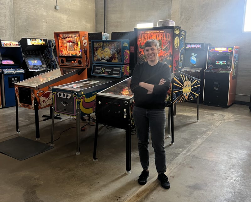 Sopko poses for a photo in front of some of the arcade machines at Upton's Naturals and Liberation Kitchen.