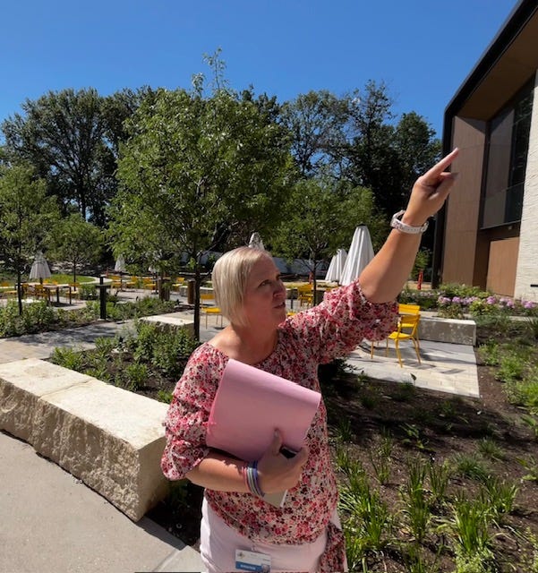 St. Louis County Library director & CEO Kristen Sorth in the Post outdoor event space points at an outdoor reading balcony at the new Clark Family Branch in Ladue
