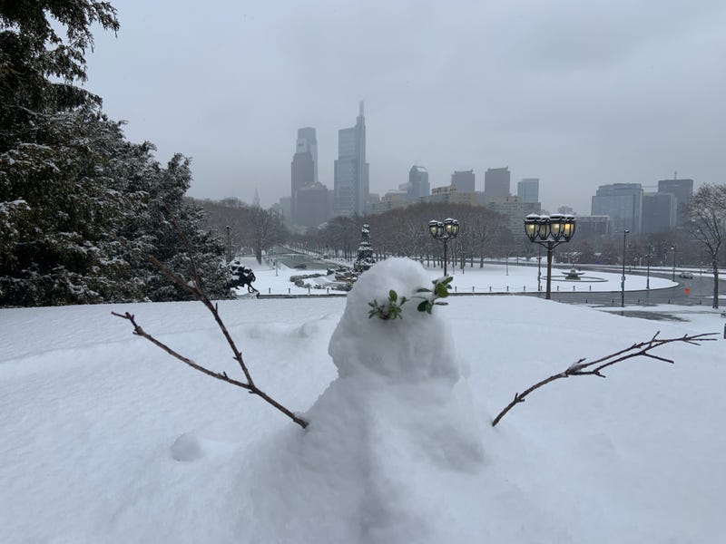 A small snowperson is covered in a blanket of fresh snow outside the Philadelphia Museum of Art.