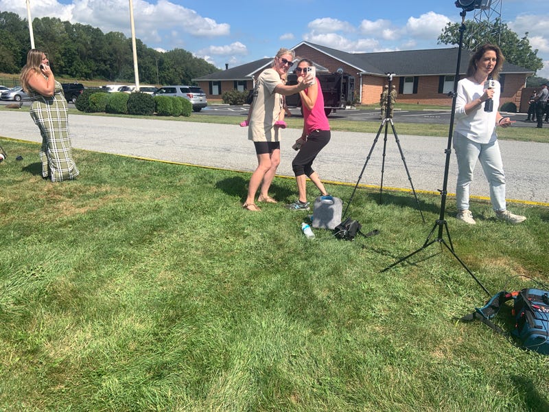 Community members pose for a selfie, with the armored vehicle that will take Danelo Cavalcante to prison in the background.