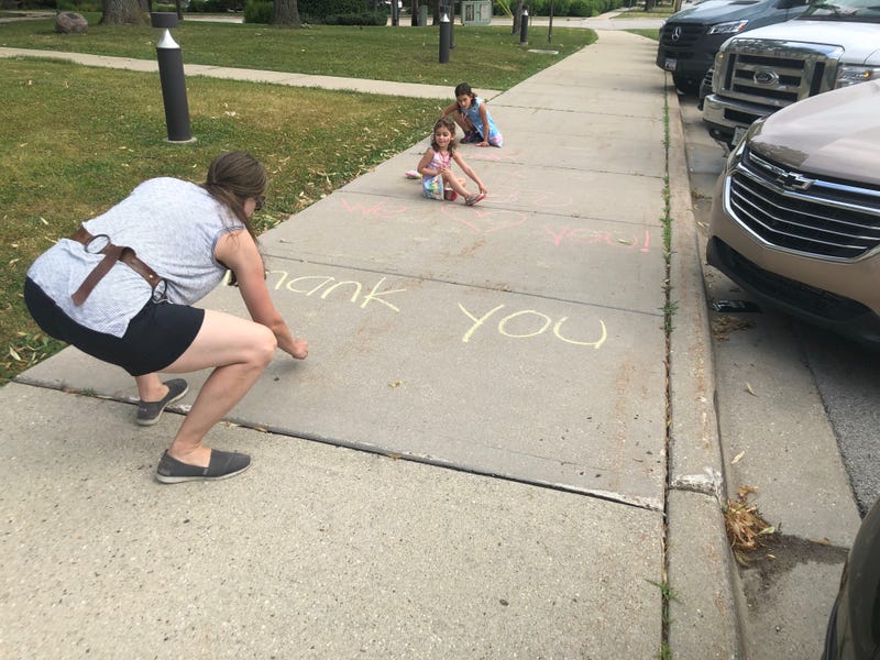Highland Park family writing chalk messages to police