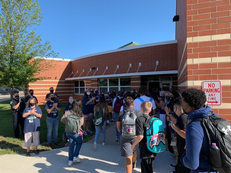 Kenyon Woods Middle School students arrive for the first day of school as their teachers cheer them on.