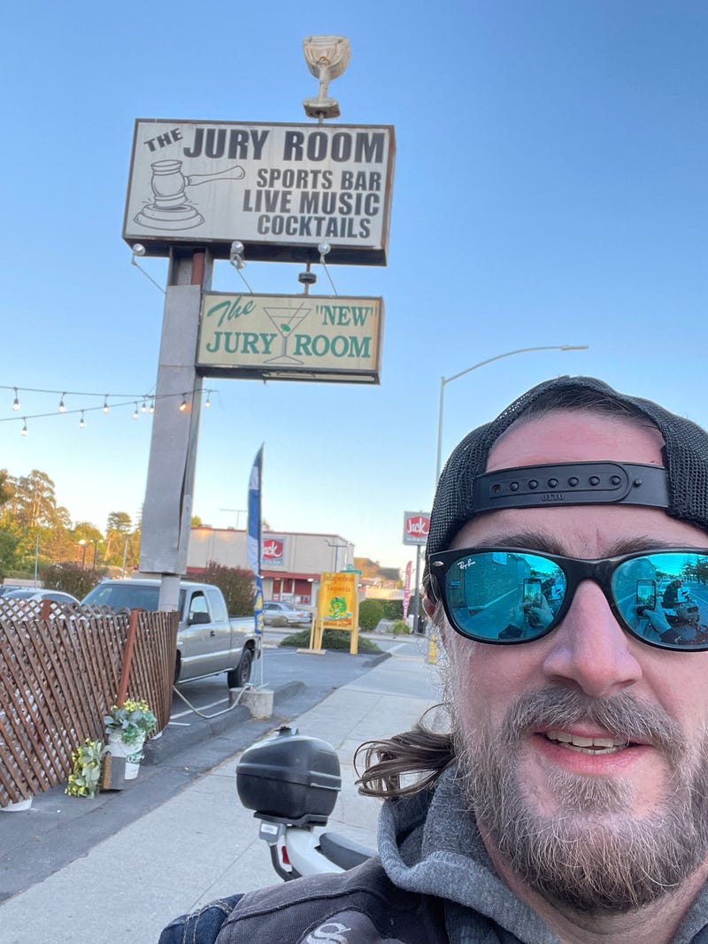 guy with a hat on in front of a sign